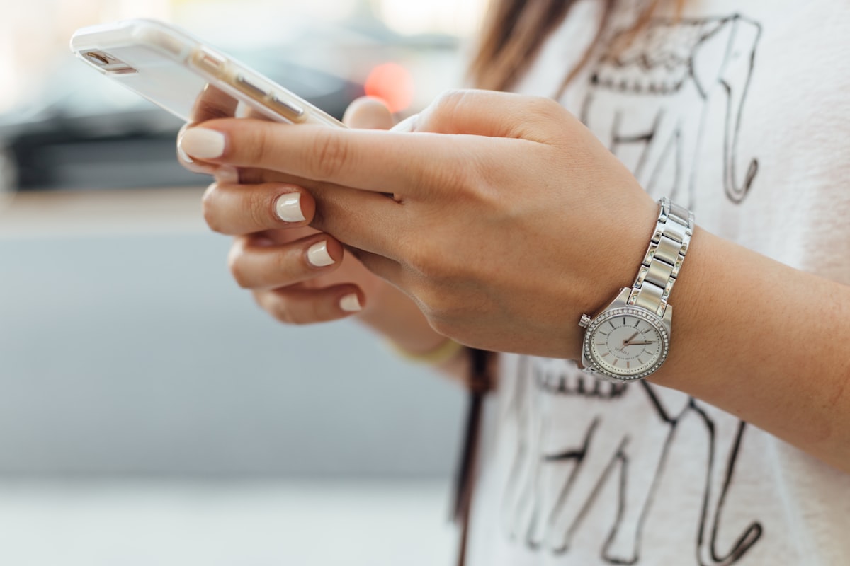 Hands holding a smartphone in warm daylight — booking a visit in a moment.